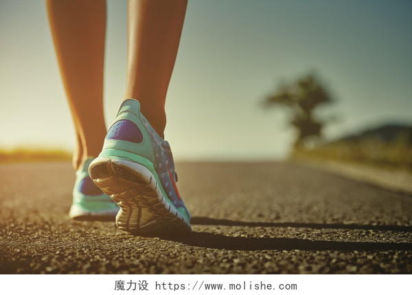 女子穿着浅蓝色运动鞋在夕阳下的马路上奔跑运动健身户外跑步